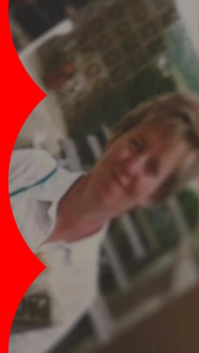 Blurred and old photo of a woman wearing a white shirt and holding a newspaper. She has dark blonde hair.