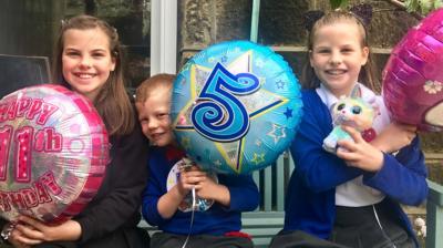 siblings-hold-balloons-for-their-birthday