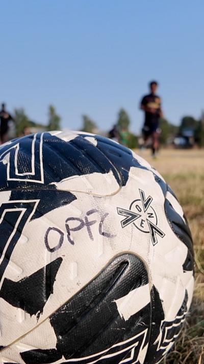 A football with OPFC written on it against a blue sky.