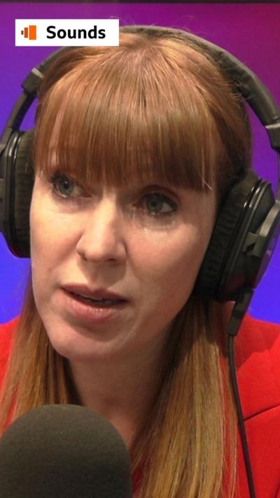 Angela Rayner wearing headphones, in front of a mic, wearing a red blazer.