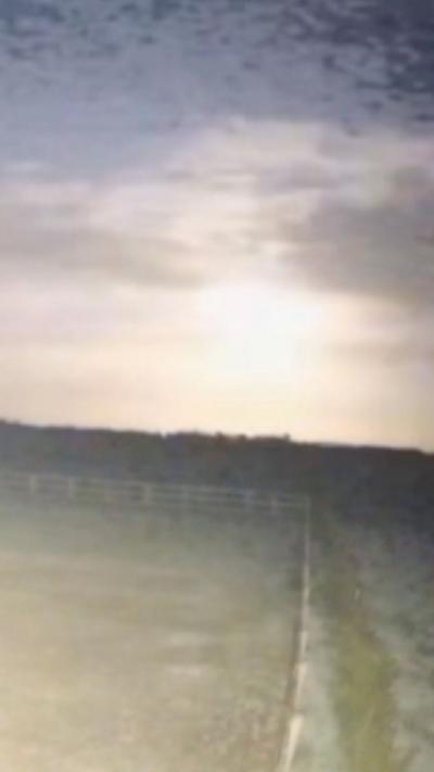 A glowing object breaking through the clouds in the distance.