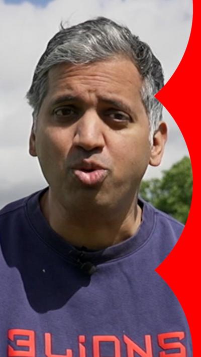 Faisal Islam wearing a dark blue jumper with 3 lions written on it in red. 