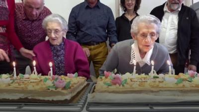 Twins Marie and Genevieve blowing out their candles