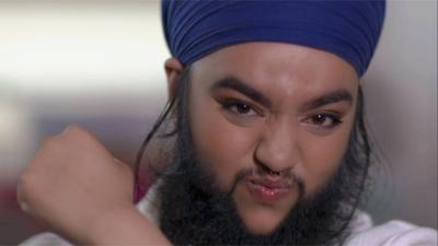 Woman with a beard and moustache wearing a blue turban