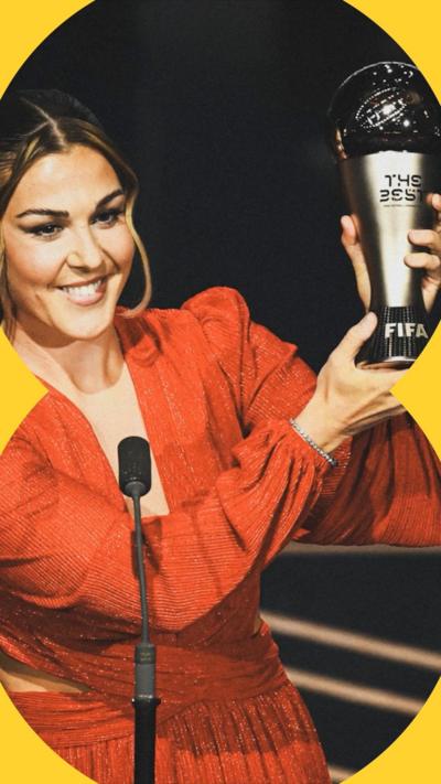 Mary Earps holds up a trophy while smiling. She has brown hair tied into a ponytail and is smiling.