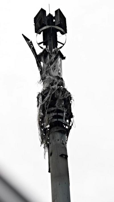 A close up image of a burnt 5G mast. There are frayed wires stemming out from the top of the mast and some melted metal.