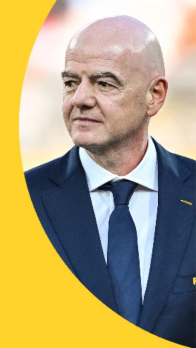 Gianni Infantino wearing a navy blue suit and tie. The Fifa logo is written in yellow on his suit pocket.