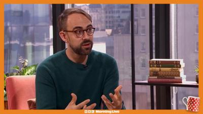 Harry Kind in the Morning Live studio sat on an orange chair, wearing a dark green jumper.