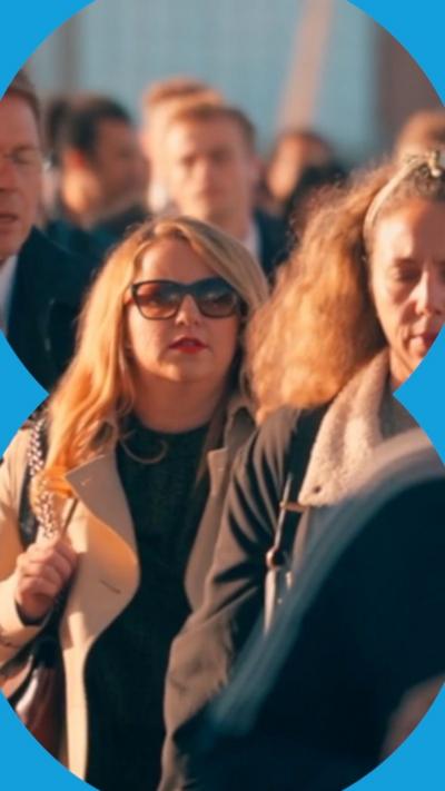 A crowd of people walk in the sun