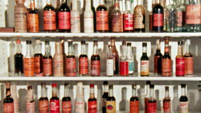 Rows of various makes of Worcestershire sauce in bottles on a shelf. 