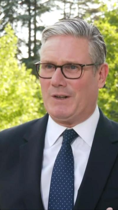 Sir Keir Starmer in a black suit and navy blue tie with white dots
