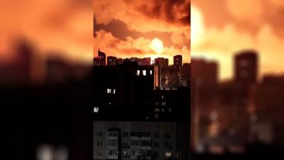 Explosions light the sky orange over a cityscape.