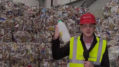 Dan Johnson holding plastic bottle in front of mounds of plastic