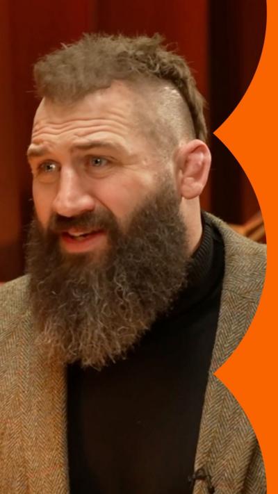 Joe Marler wearing a green blazer, pulling a concerned face.