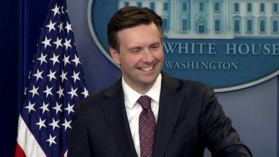 Press secretary Josh Earnest smiles as he speaks to journalists