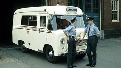 Two men standing in front of a London ambulance.