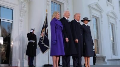 Jill and Joe Biden smile on the steps of the White House, as they stand next to the Trumps