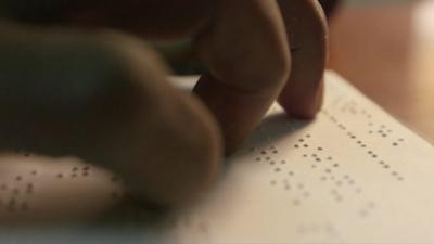 hand on a page reading braille