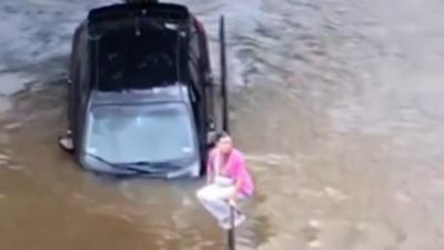 Woman abandons a vehicle after driving on a flooded parking lot in Texas