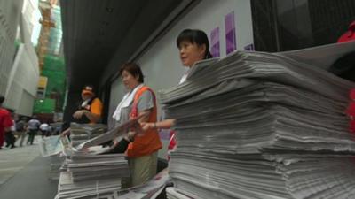 Women handing out newspapers in Hong Kong