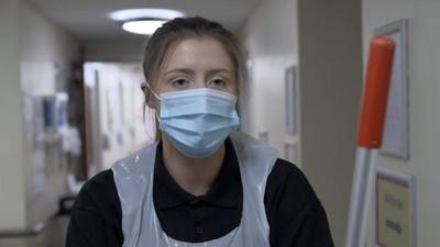 Hannah walking down a corridor in PPE safety clothing