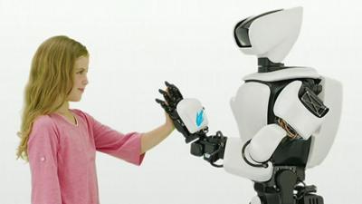 A girl (L) faces Toyota's T-HR3 humanoid robot (R)