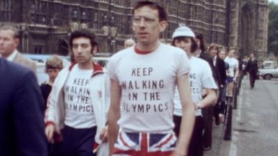 A black and white image of a group of protestors wearing t shorts with a KEEP WALKING IN THE OLYMPICS slogan.