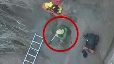 Ladders works to rescue a hiker stuck in quicksand (circled).