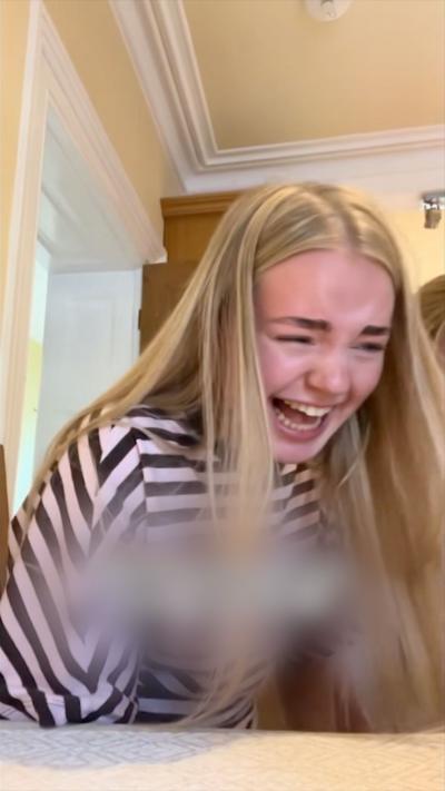 Blonde woman smiling and wearing striped pink and brown t-shirt