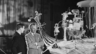 Rowland Emett and Kenneth Allsop look on at his invention which is made of propellors, umbrellas and a rug.