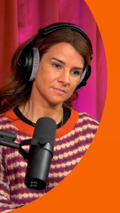 Izzy Judd, wearing a striped jumper and headphones, sitting behind a microphone