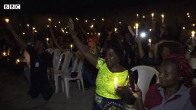 People kneeling and holding candles