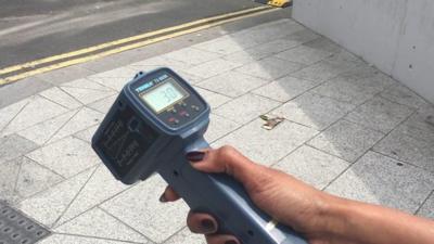Temperature gun held over pavement