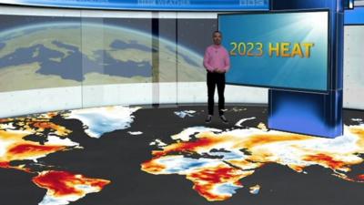 Ben Rich standing on a map of the globe showing temperature anomalies