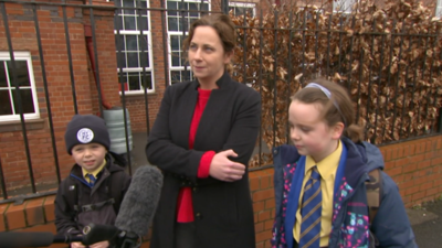 Mother and children outside school gates