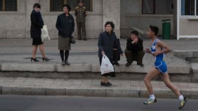 Runner watched by passers-by