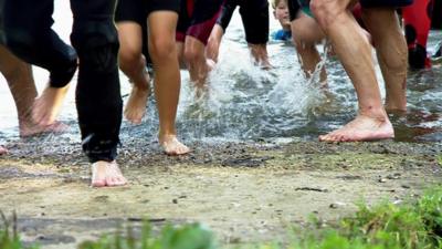 various feet and legs of triathletes coming out of the water during a race