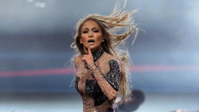 Jennifer Lopez, wearing a black and transparent outfit performing on stage at the AMAs