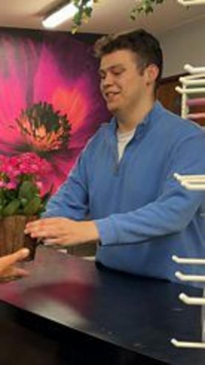 Jamie in a blue fleece handing over a plant 