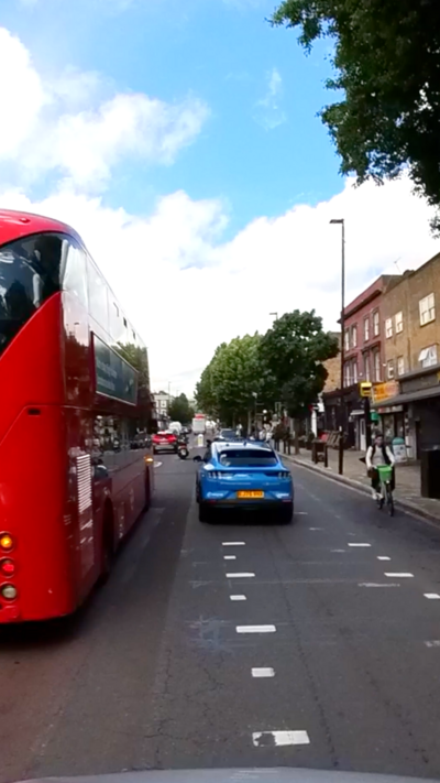 A blue driverless minicab passes a London double decker bus on a London high-street