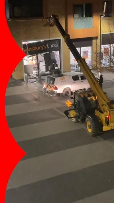 Phone footage from window shows yellow telehandler in middle of street pulling cash machine from Sainsburys