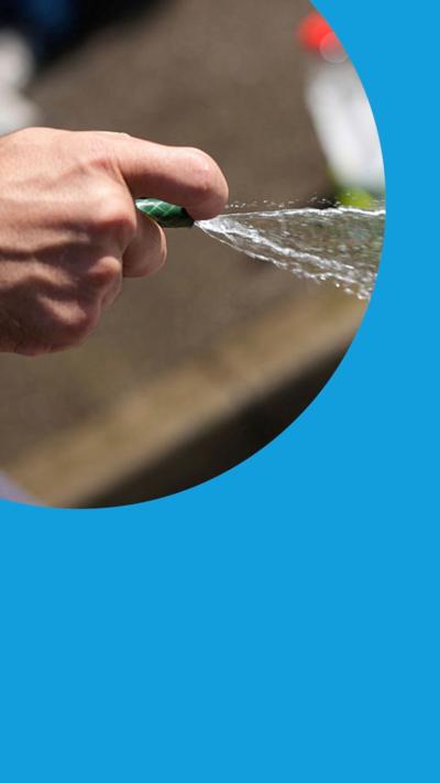 A man uses a hosepipe to clean a carpet in the street in Leeds