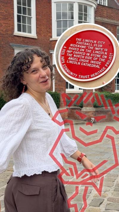 Young woman with short, brunette curly hair walks away from camera. Red plaque on Lincoln City can be seen.