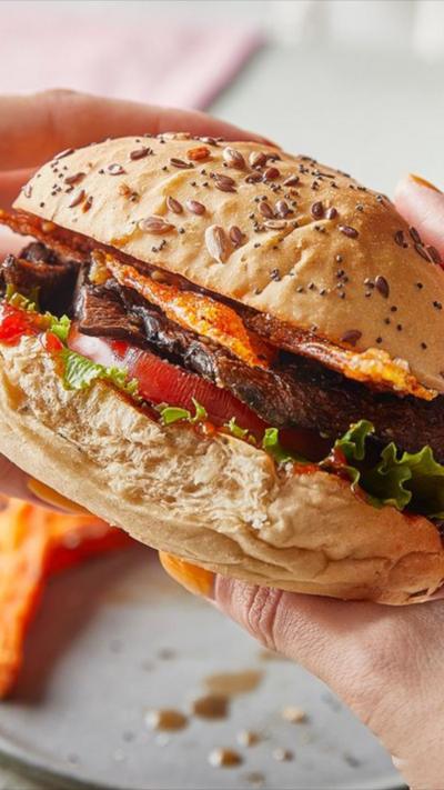 A pair of hands holds a mushroom burger in a bun.