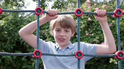 A boy on a climbing frame net