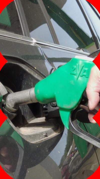 A green pump going into a car as someone fills up their tank. 