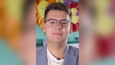Nazarii Lialiuk in a white t-shirt and light blue blazer. He is wearing glasses with a half black rim.