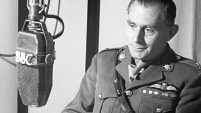 A man in a military uniform looking at a ý-labelled microphone