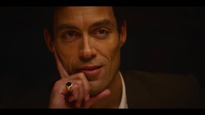 A man stares into the camera wearing a signet ring and his hand on his face