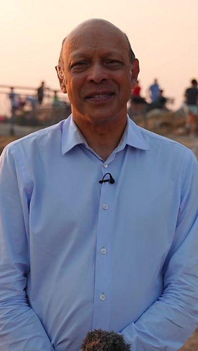 Pallab looking at the camera, several people visible behind him